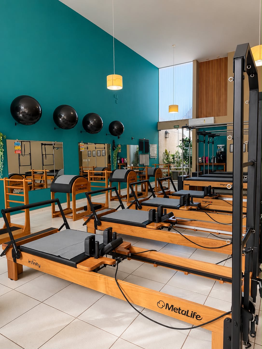Sala do estúdio GA Pilates em Assis com aparelhos de Pilates em madeira e parede turquesa